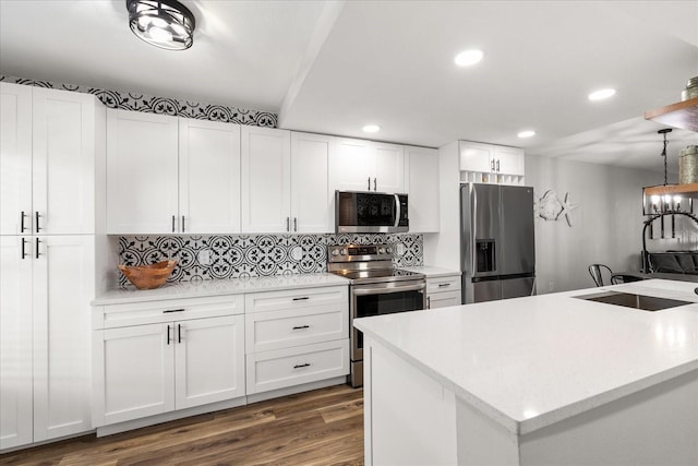 kitchen featuring tasteful backsplash, appliances with stainless steel finishes, decorative light fixtures, light countertops, and white cabinetry