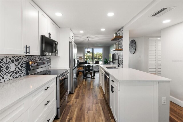 kitchen featuring stainless steel appliances, a sink, white cabinets, light countertops, and an island with sink