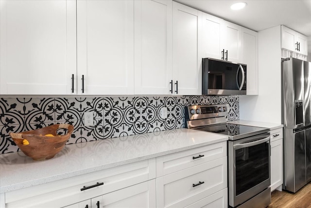 kitchen featuring appliances with stainless steel finishes, white cabinets, backsplash, and light stone counters