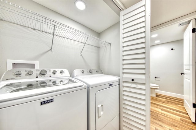 washroom with baseboards, laundry area, separate washer and dryer, and light wood-style floors