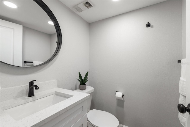 half bath with visible vents, a textured wall, toilet, vanity, and recessed lighting