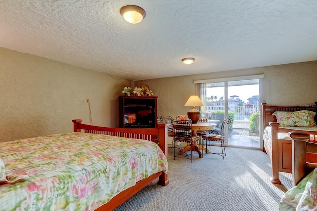 carpeted bedroom featuring a textured ceiling, a textured wall, and access to exterior