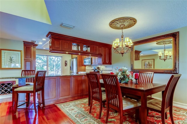 dining area with a chandelier, dark wood-style flooring, a textured ceiling, and visible vents