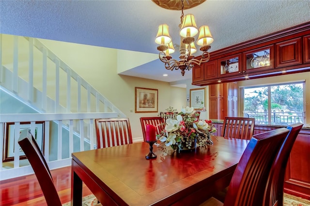 dining space featuring a textured ceiling, a notable chandelier, and wood finished floors