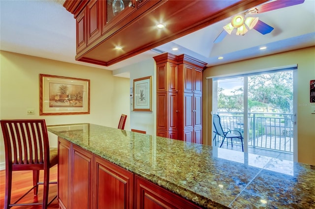 kitchen featuring stone counters, recessed lighting, glass insert cabinets, and ceiling fan