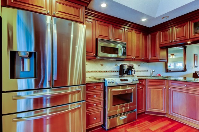 kitchen featuring light stone counters, recessed lighting, light wood-style flooring, backsplash, and appliances with stainless steel finishes