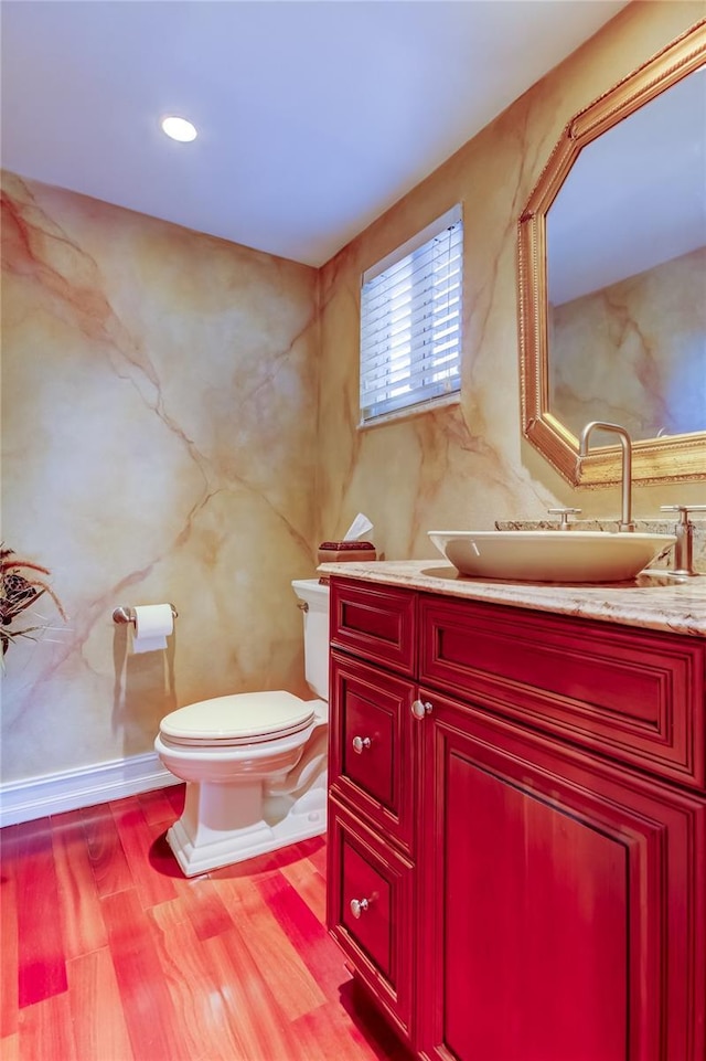 half bathroom featuring vanity, wood finished floors, and toilet