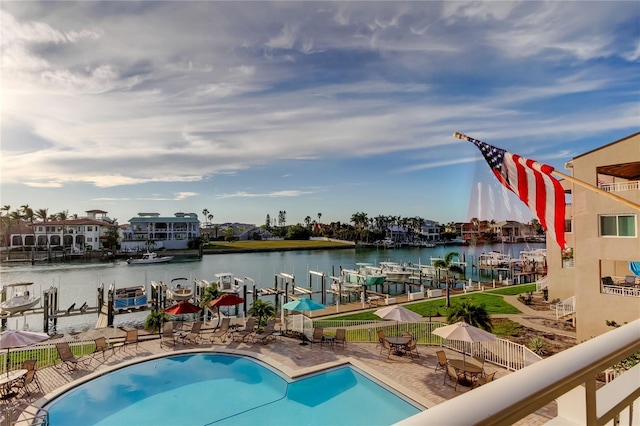 community pool with a water view, fence, and a patio