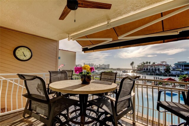 balcony featuring outdoor dining space, a water view, and a ceiling fan