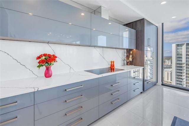 kitchen featuring tasteful backsplash, modern cabinets, light stone countertops, a view of city, and black electric cooktop