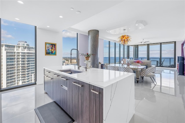 kitchen featuring a water view, a sink, floor to ceiling windows, an island with sink, and modern cabinets