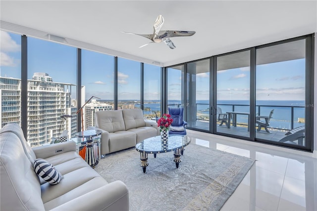 tiled living area featuring ceiling fan, a water view, and floor to ceiling windows