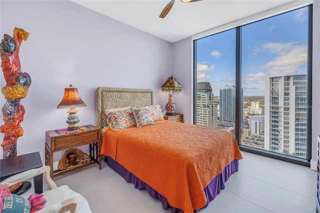 bedroom featuring a view of city, ceiling fan, and a wall of windows