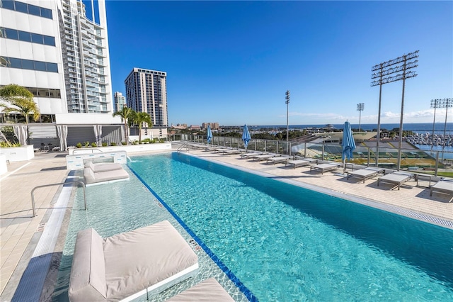 pool featuring a view of city, a water view, a patio, and fence