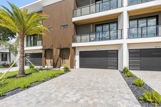 view of front of property featuring an attached garage, decorative driveway, and stucco siding