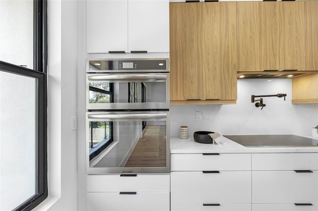 kitchen featuring stainless steel double oven, black electric cooktop, white cabinetry, light countertops, and modern cabinets