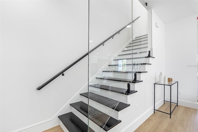 staircase featuring wood finished floors and baseboards