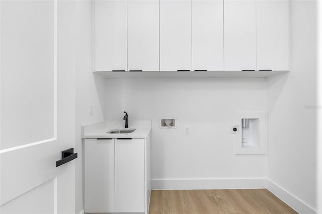 laundry area with washer hookup, cabinet space, light wood-style flooring, a sink, and baseboards