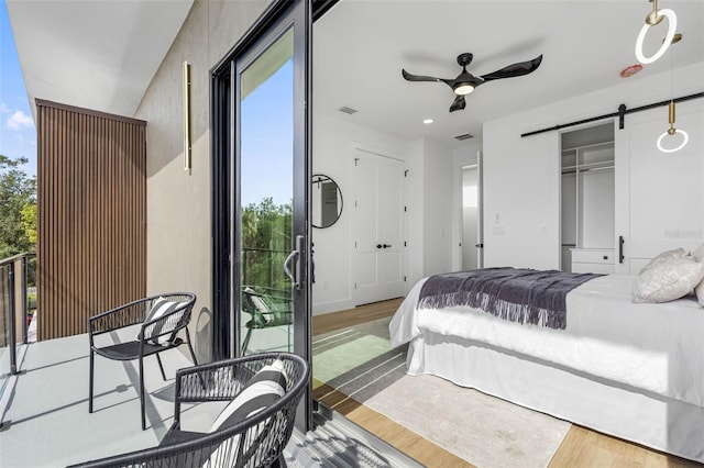 bedroom featuring light wood-style floors, a barn door, visible vents, and baseboards