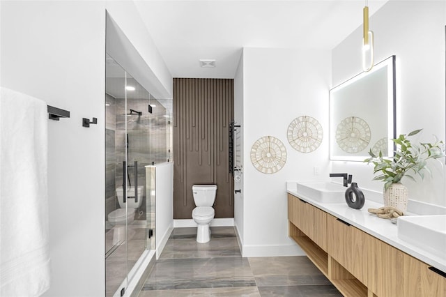 full bathroom featuring toilet, a sink, baseboards, a shower stall, and double vanity