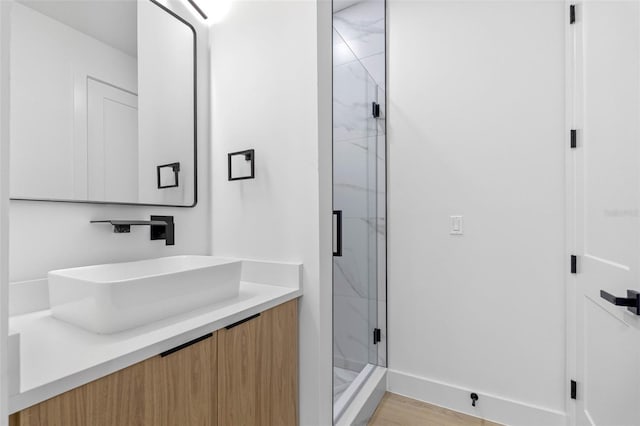 bathroom with baseboards, a shower stall, vanity, and wood finished floors