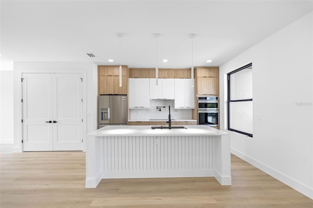 kitchen featuring white cabinets, modern cabinets, stainless steel appliances, light countertops, and pendant lighting