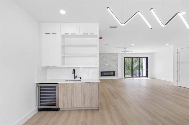 bar with wine cooler, a premium fireplace, a sink, visible vents, and light wood-type flooring