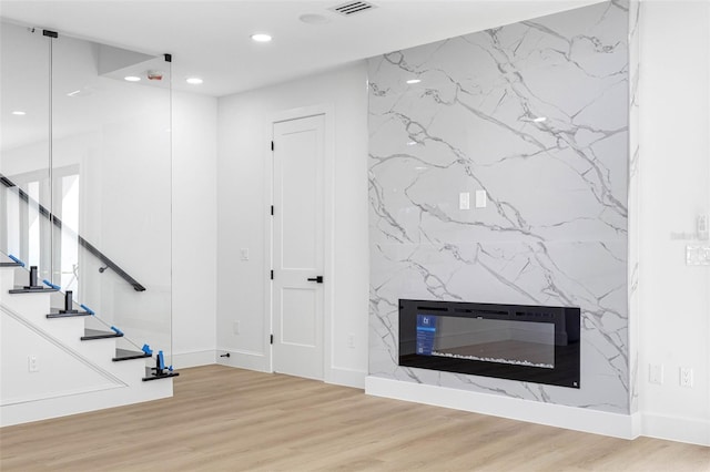 unfurnished living room with stairway, wood finished floors, a high end fireplace, and recessed lighting