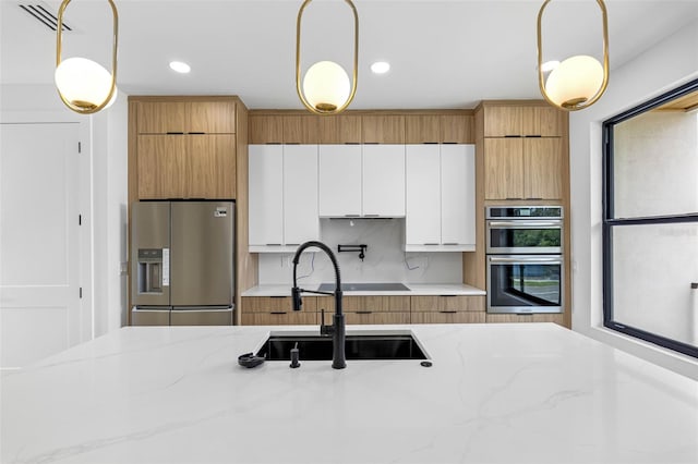 kitchen with stainless steel appliances, modern cabinets, pendant lighting, and white cabinets