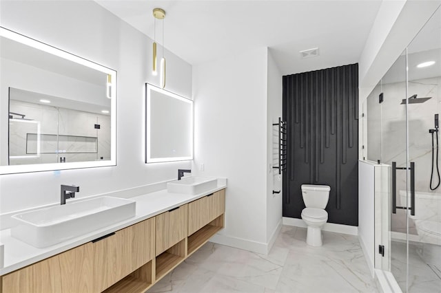 bathroom with marble finish floor, double vanity, a sink, and toilet