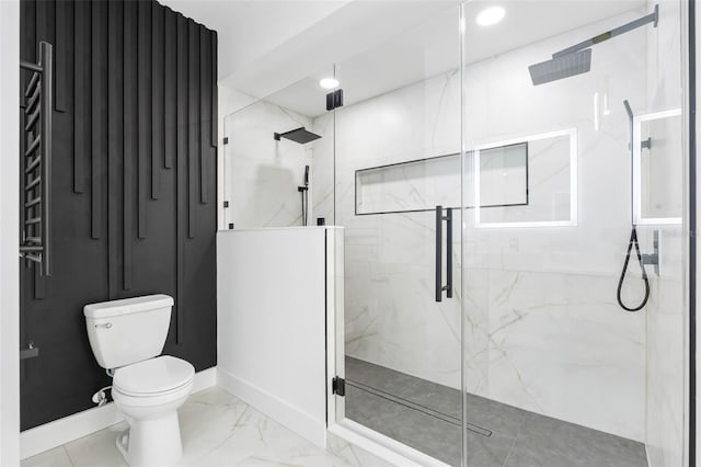 bathroom featuring toilet, marble finish floor, a marble finish shower, and baseboards