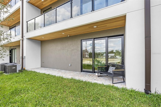 back of house featuring a yard, central AC unit, a patio area, and stucco siding