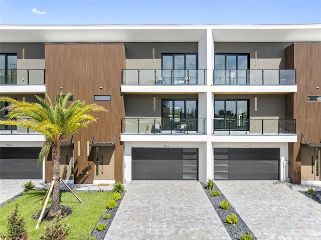 contemporary house with an attached garage, decorative driveway, and stucco siding