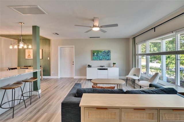 living room with ceiling fan with notable chandelier, visible vents, and light wood-style floors