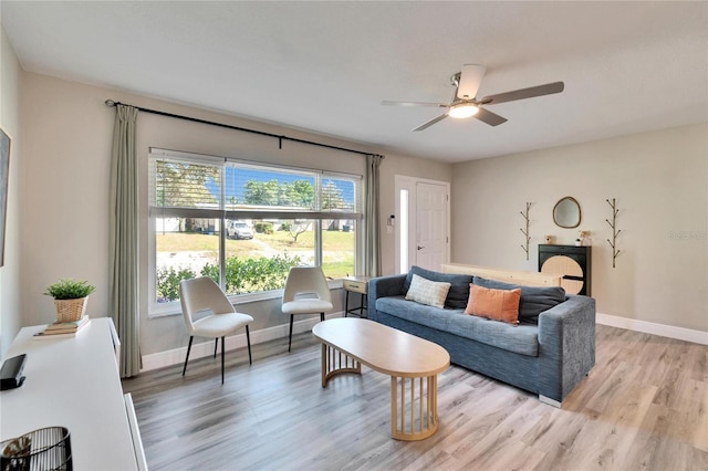 living room with light wood-type flooring, baseboards, and a ceiling fan