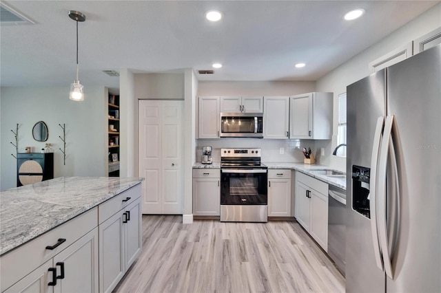 kitchen featuring appliances with stainless steel finishes, decorative light fixtures, a sink, and visible vents