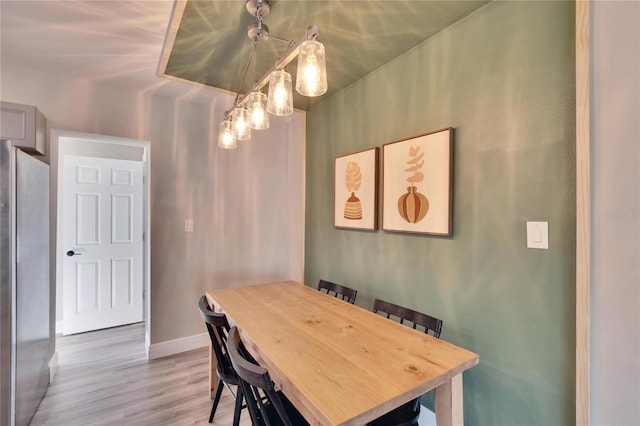 dining space featuring light wood-type flooring and baseboards