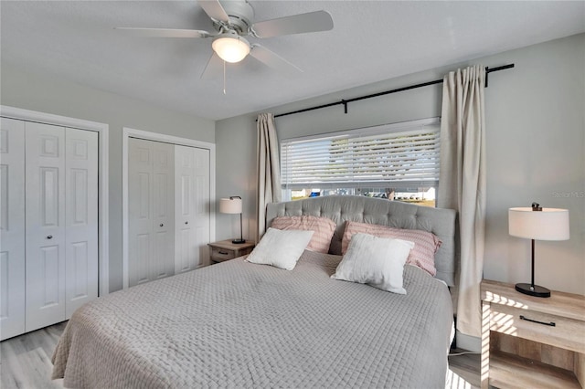 bedroom featuring two closets, a ceiling fan, and light wood-style floors