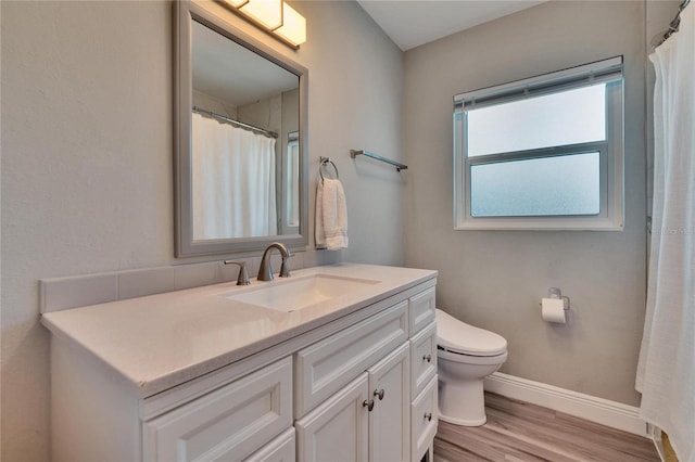 bathroom with baseboards, vanity, toilet, and wood finished floors