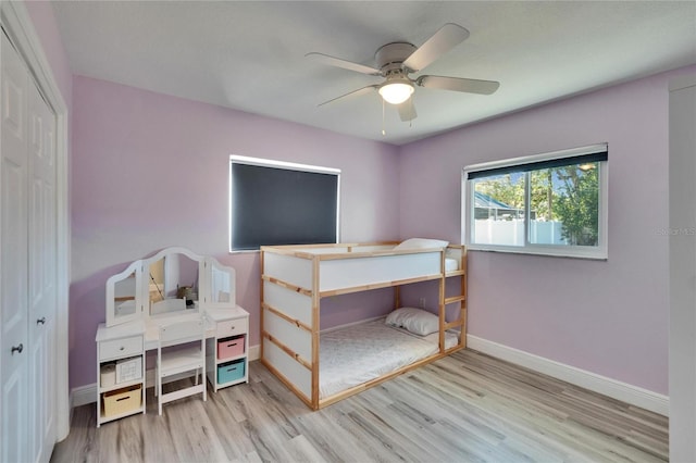 bedroom with a ceiling fan, a closet, light wood-style flooring, and baseboards