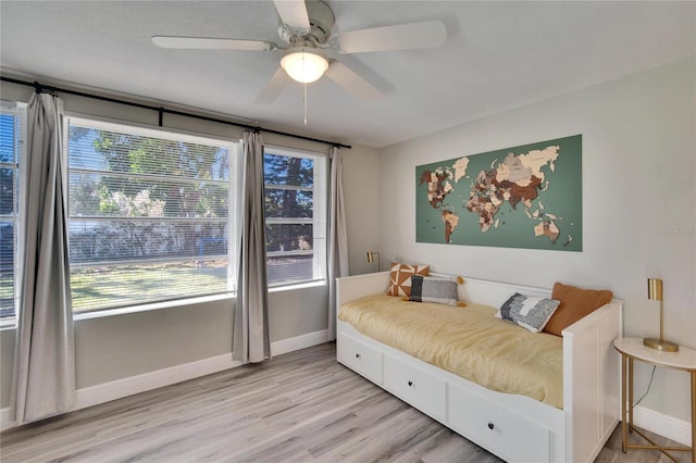 bedroom featuring light wood-type flooring, a ceiling fan, and baseboards