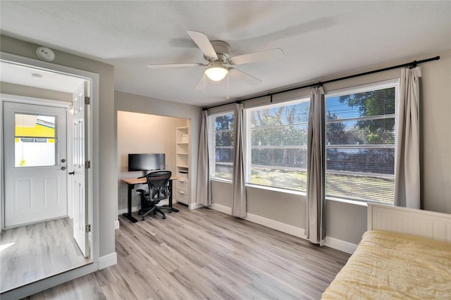 office space with a textured ceiling, light wood finished floors, a ceiling fan, and baseboards