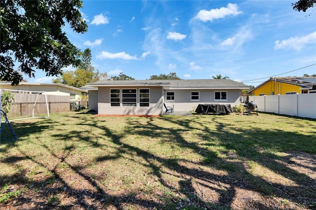 rear view of property with a fenced backyard, a lawn, and stucco siding