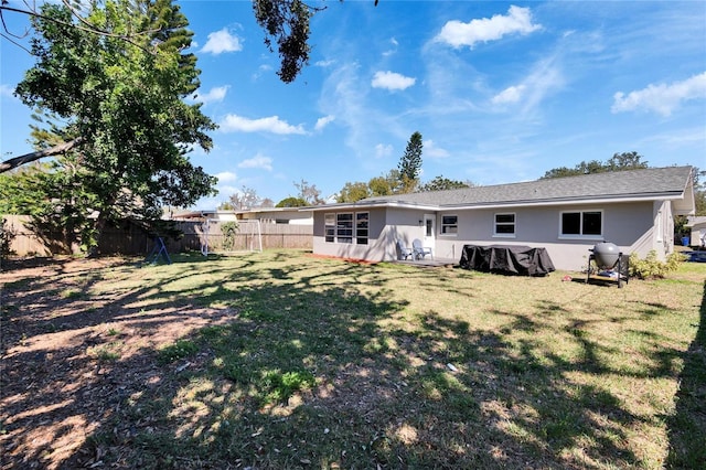 rear view of house with a fenced backyard, a lawn, and stucco siding