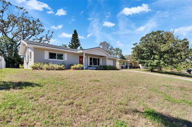 ranch-style house featuring a garage, a front lawn, and stucco siding