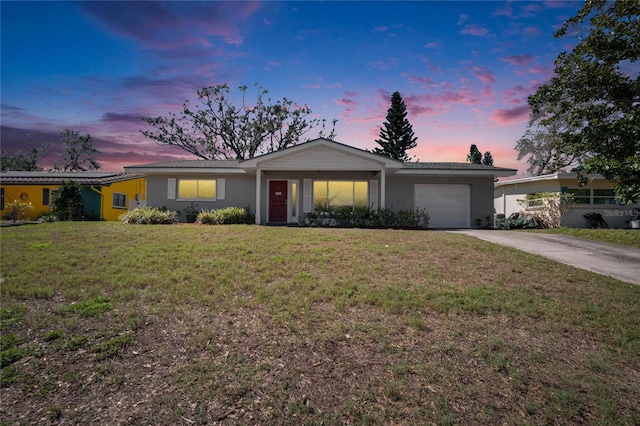 single story home with a yard, an attached garage, driveway, and stucco siding