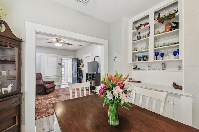 dining area featuring built in features, visible vents, ceiling fan, and wood finished floors