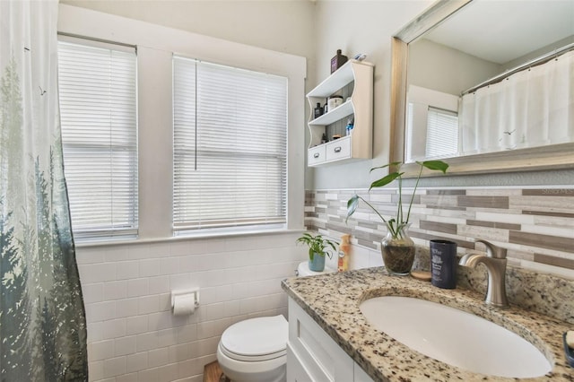 full bath with a wainscoted wall, tile walls, a shower with shower curtain, toilet, and vanity