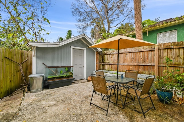 view of patio / terrace with an outbuilding, a shed, outdoor dining area, and a fenced backyard