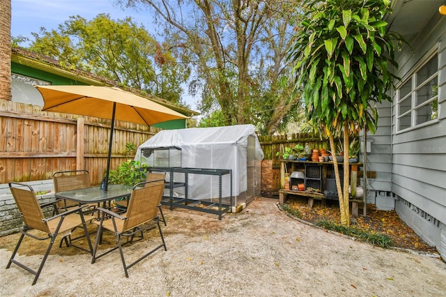 view of patio with an outbuilding, an exterior structure, fence, and outdoor dining space